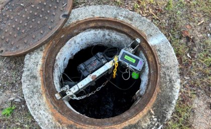 some wires and tech equipment sits inside a concrete-surrounded hole in the ground